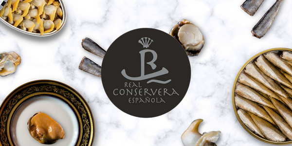 Real Conservera Espanola with Galician Cockles, Pickled Mussels, and Spanish Sardines on top of a Marble Counter